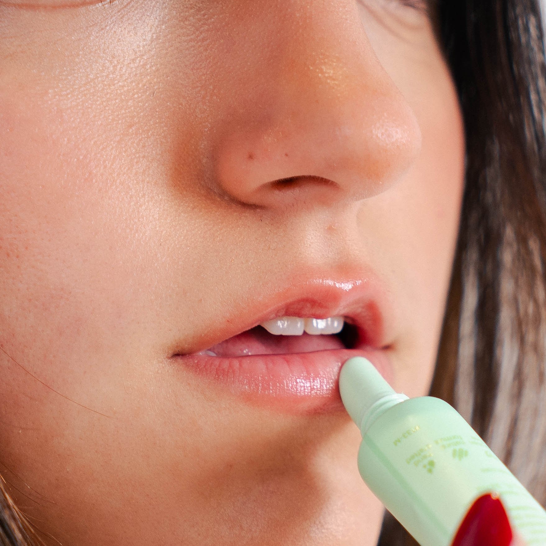 Woman applying mint lip balm to her lips