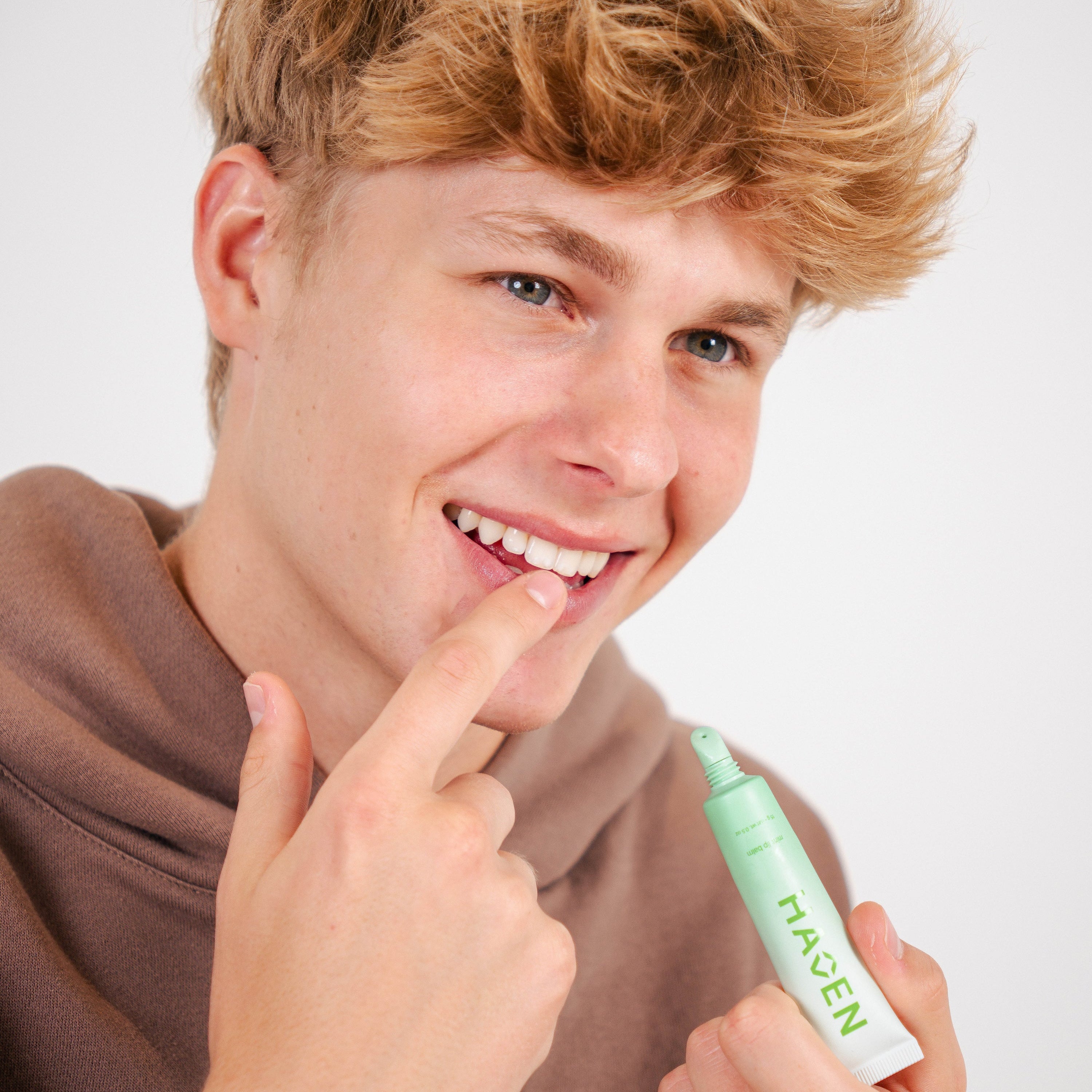 Haven applying mint lip balm to his lips.